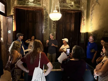 Ulisses compartilhando histórias durante caminhada dentro de um edifício histórico