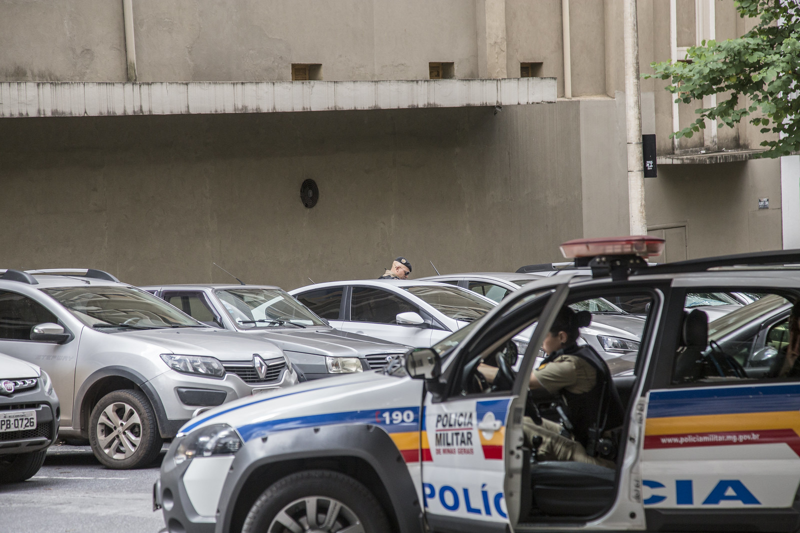 Carros estacionados e uma viatura da Polícia Militar de Minas Gerais