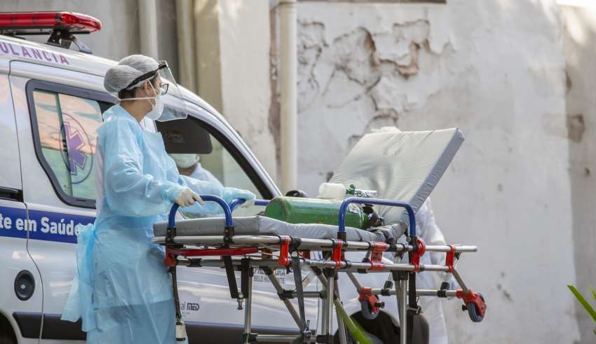 Funcionário da Saúde leva maca com oxigênio para atendimento de paciente