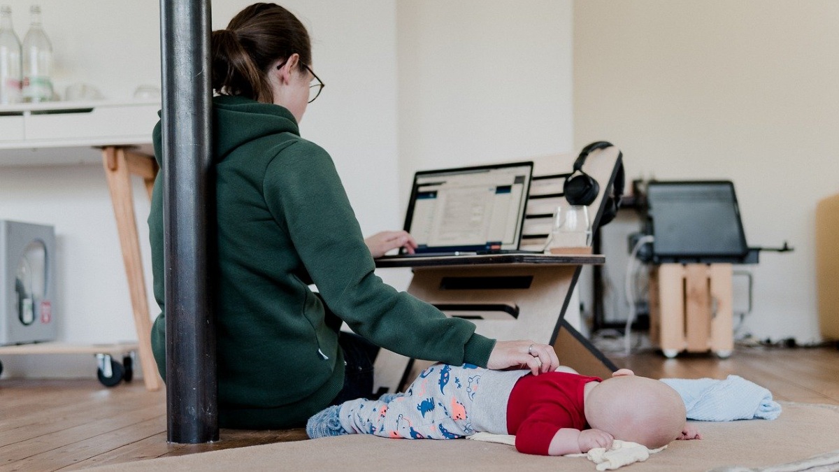 mãe trabalha em computador ao lado de bebê