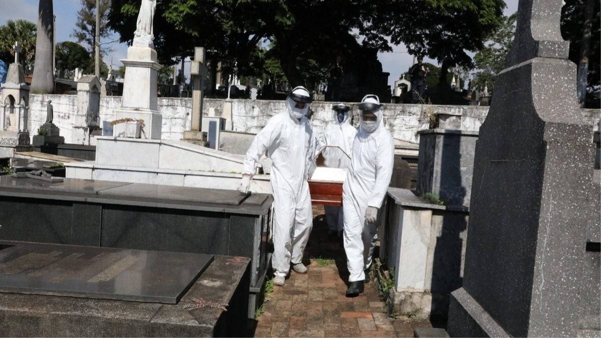 Funcionários de cemitério carregando caixão