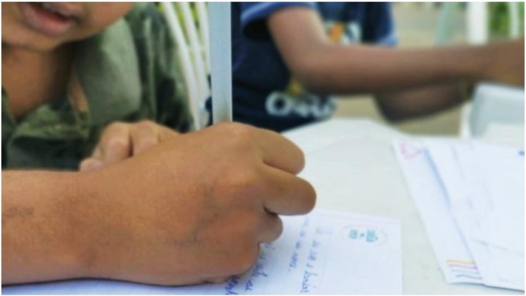 criança escrevendo em uma folha de caderno na escola