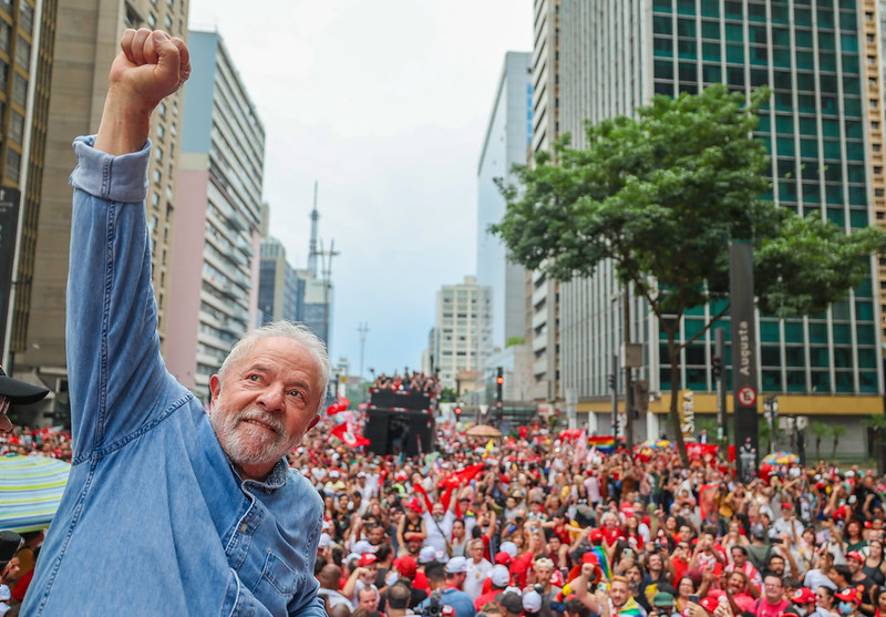 Lula com o braço direito erguido e manifestantes na avenida Paulista