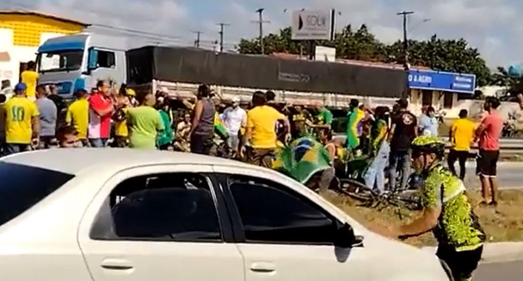 Homem vestido de ciclista se joga sobre carro fingindo ser atropelado