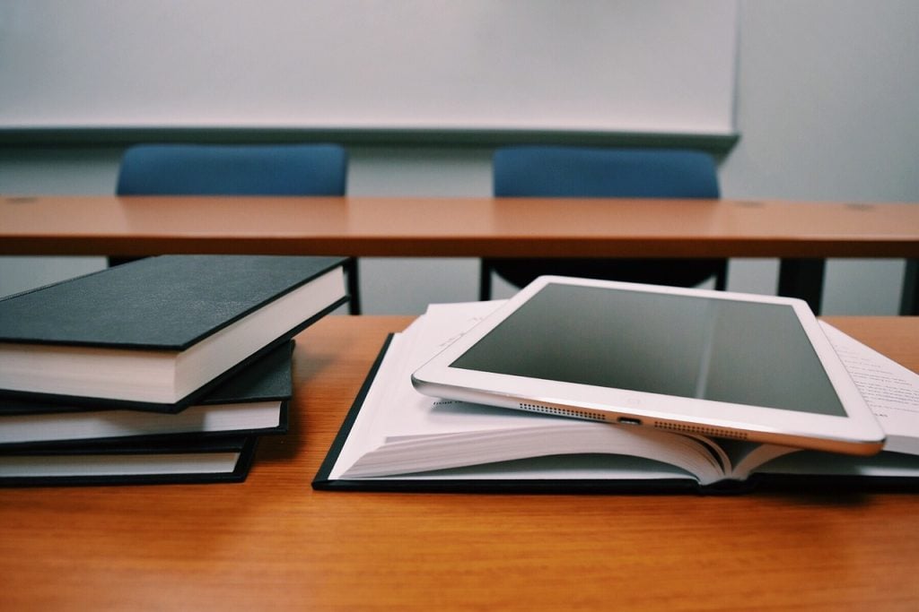 sala de aula com tablet, livro e cadernos