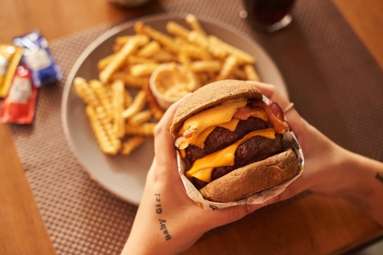 hamburgueria bh - mulher segura lanche com prato de batatas