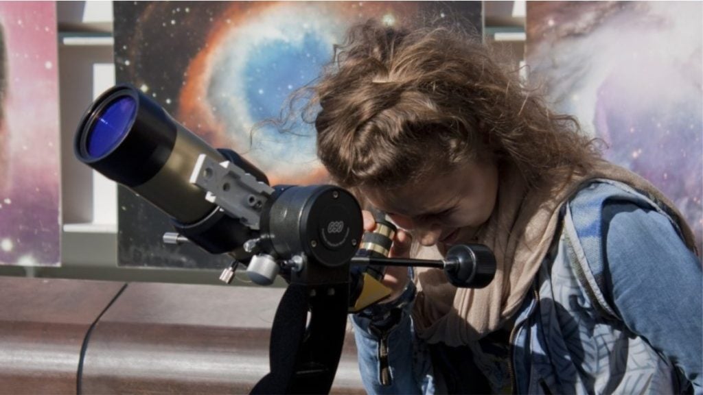 jovem observa em telescópio